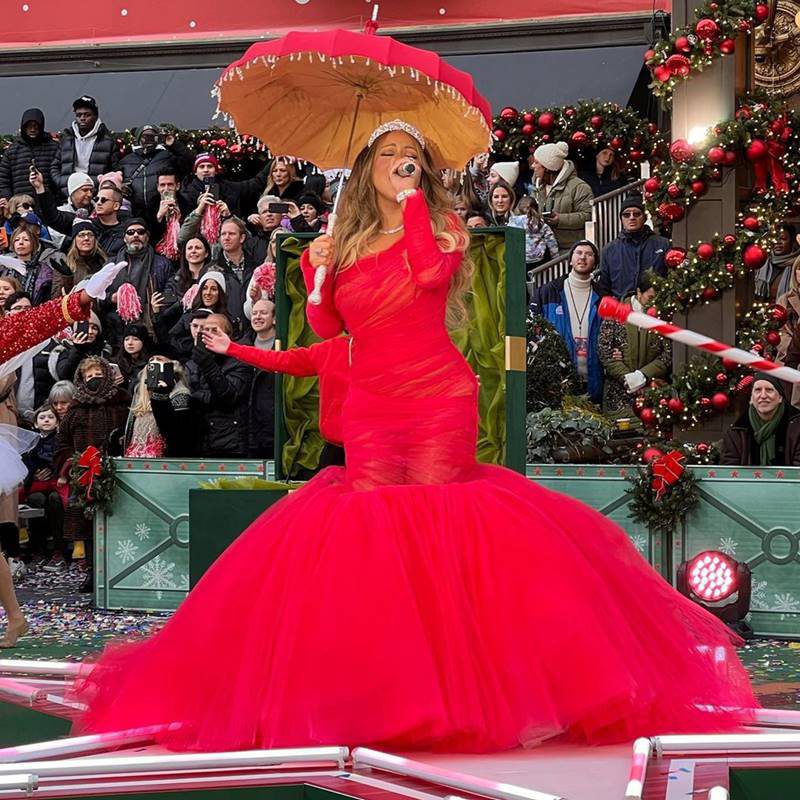 Mariah Carey de vestido vermelho segurando sombrinha e microfone - metrópoles