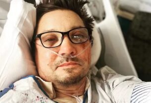 Jeremy Renner em uma cama de hospital. Ele usa óculos de grau e está com o rosto machucado - Metrópoles